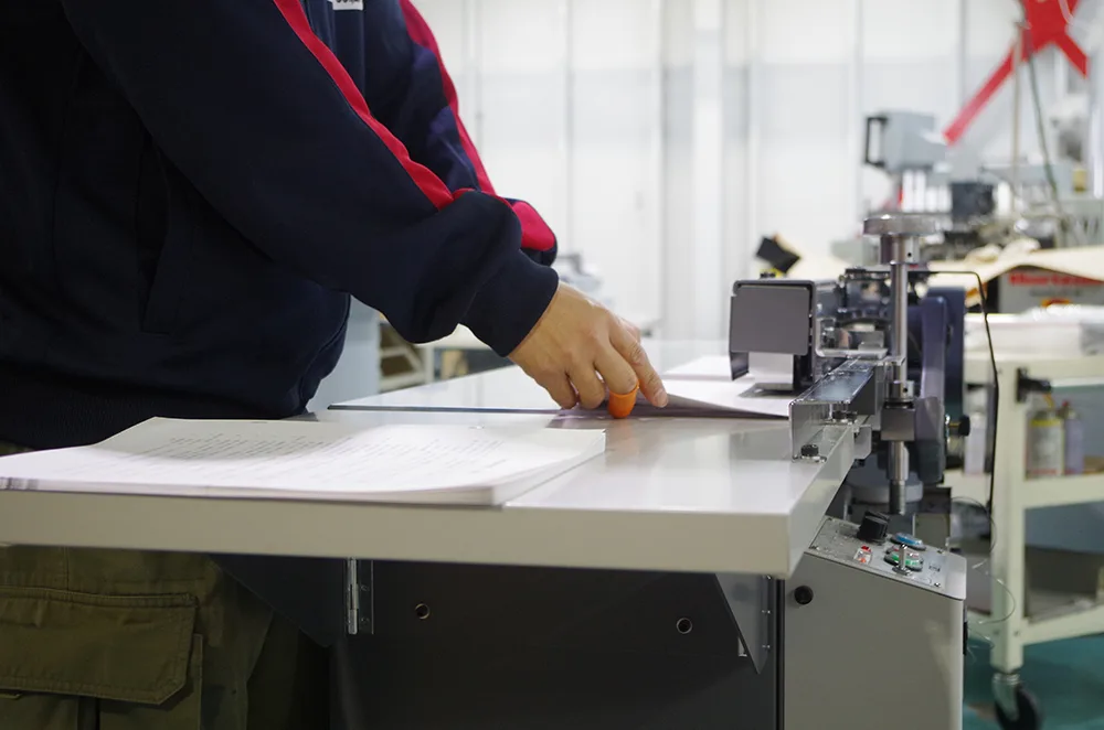 自社工場で冊子を製本するスタッフ